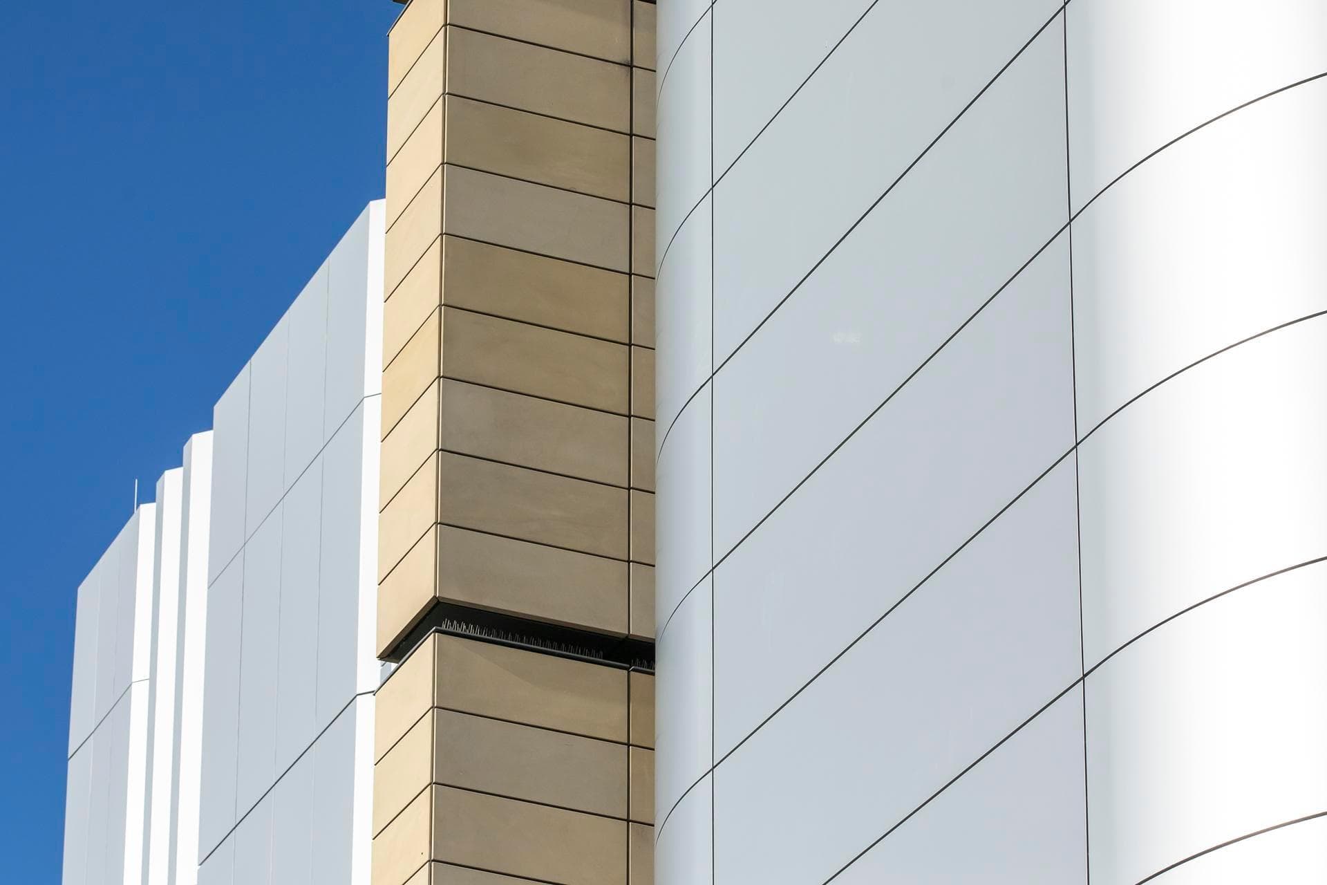 Close-up of Alpolic NC silver and beige façade panels on the Charles Perkins Centre, showing the contrast of curved and flat surfaces.