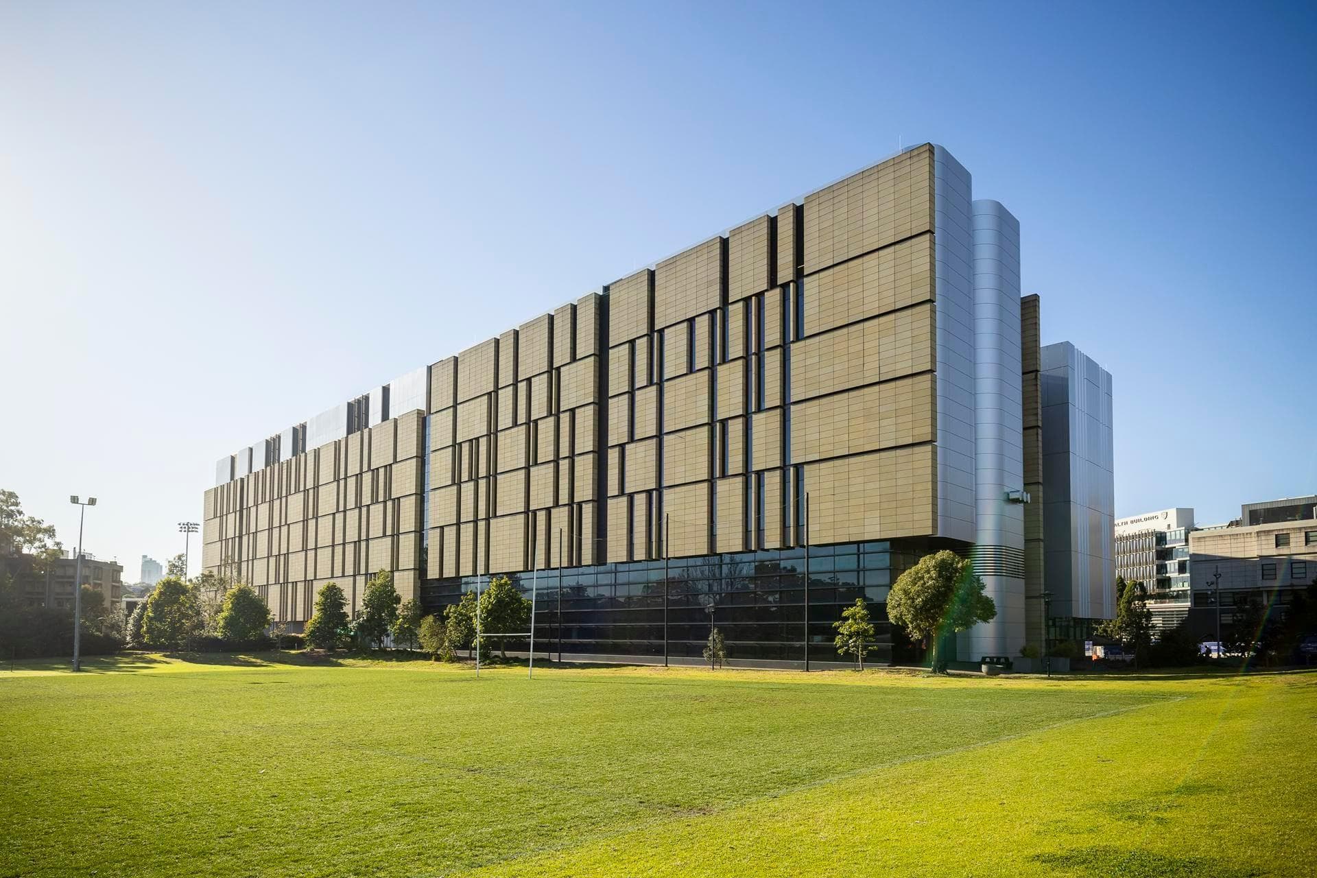 Alpolic NC white façade panels on the Charles Perkins Centre, with sharp vertical edges against a clear blue sky.